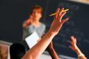 Teacher pointing to raised hands in classroom.