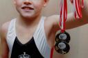 Gymnast: Daniel Burdock aged eight, holds up some of his previous medals. He has been selected to go to Russia for intensive training.
