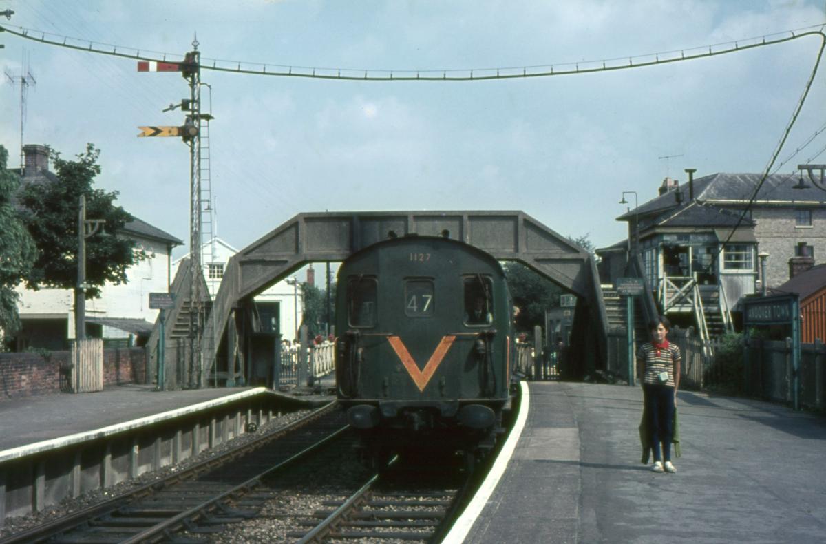 A DMU pulls into Andover Town SAtation heading for Southampton. The level crossing gates are shut across the A303 (Bridge Street).

Picture from the Jeffery Saunders collection
