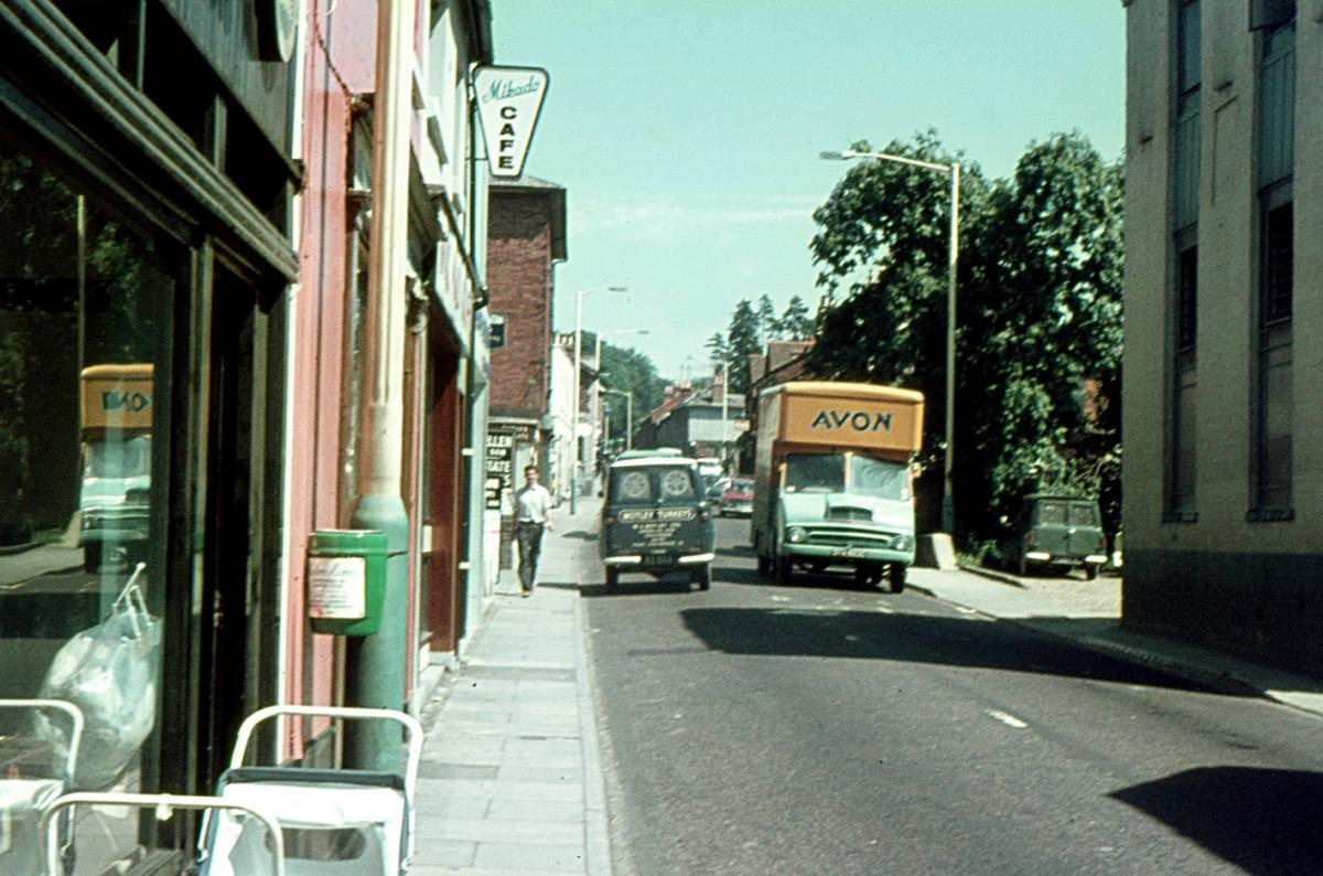 London Street (A303) looking east with it's two-way traffic. On the pavement are push chairs - not café tables!  The Mikado Café like all eating and drinking establishments catered INDOORS for the 50% of the adult population who smoked (today about 22%)