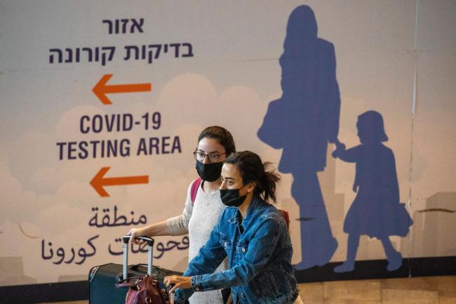 Travellers wearing face masks arrive at Ben Gurion Airport
